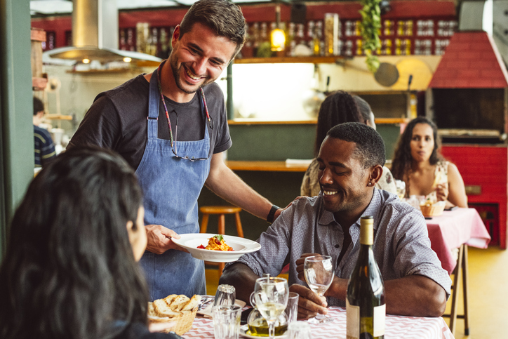 Camarero atiende a clientes en mesa de restaurante