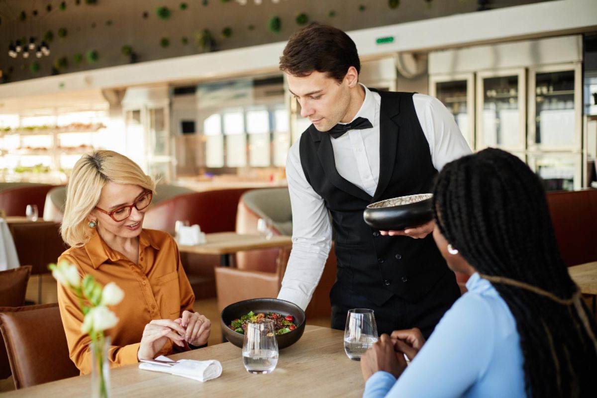Camarero sirve dos platos en una mesa a dos clientas del restaurante