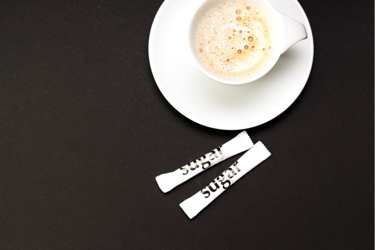 taza de café con sobres de azúcar sobre el plato