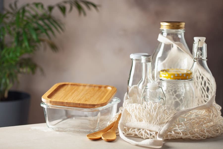 Envases de vidrio, cucharas de madera y una bolsa de malla sobre una mesa