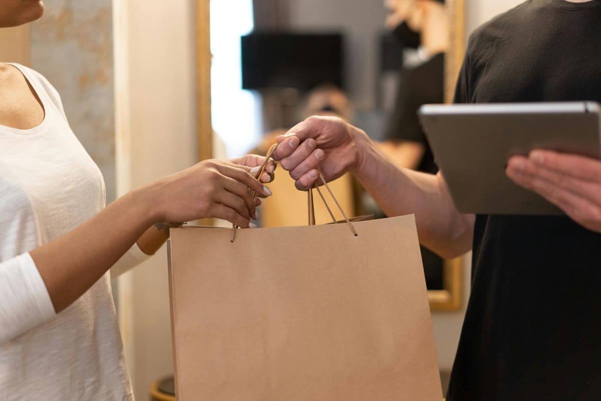 Un camarero entrega una bolsa a una clienta
